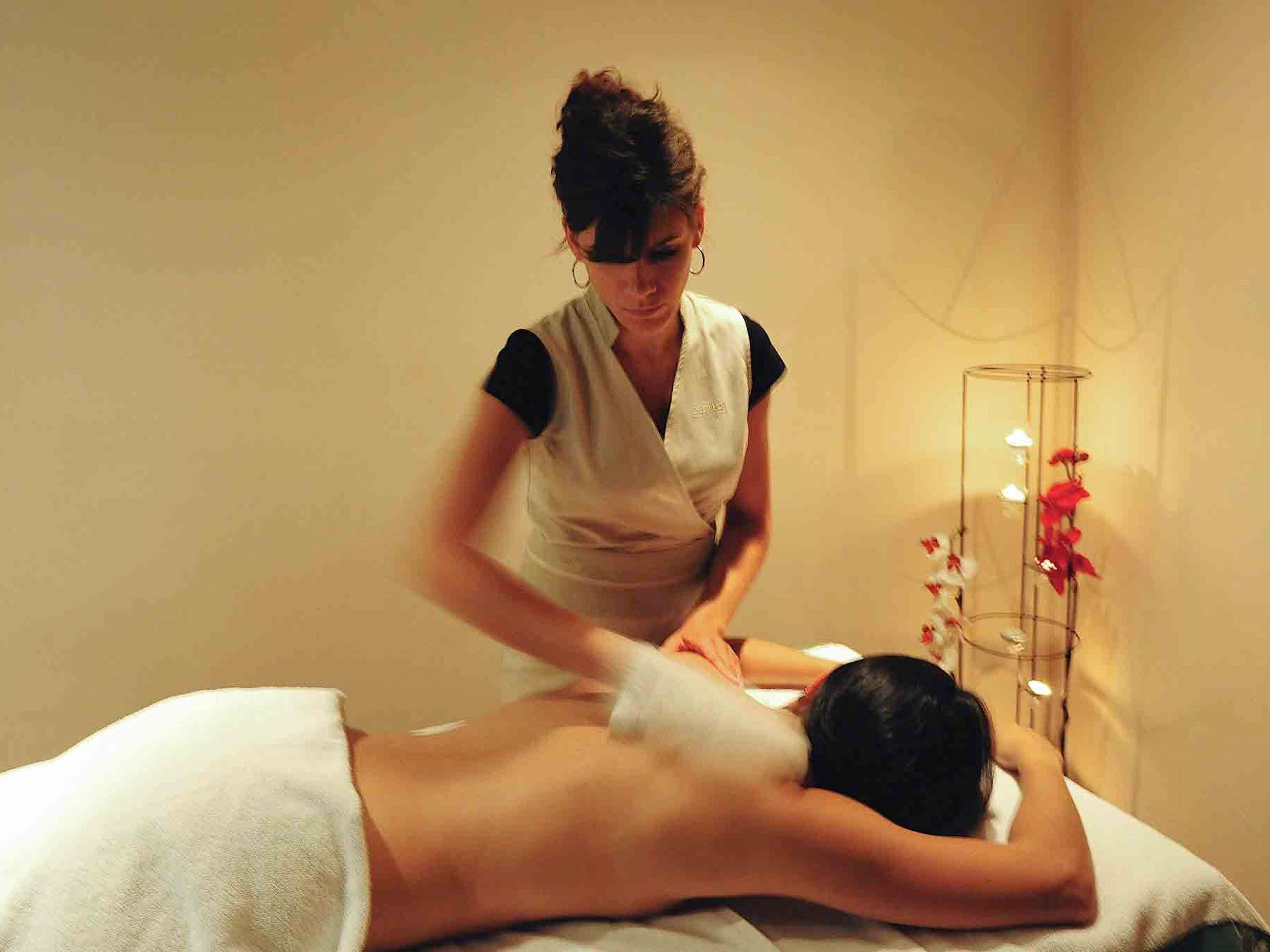 A massage therapy session in a room with a simple, neutral decor and a single vase of flowers.