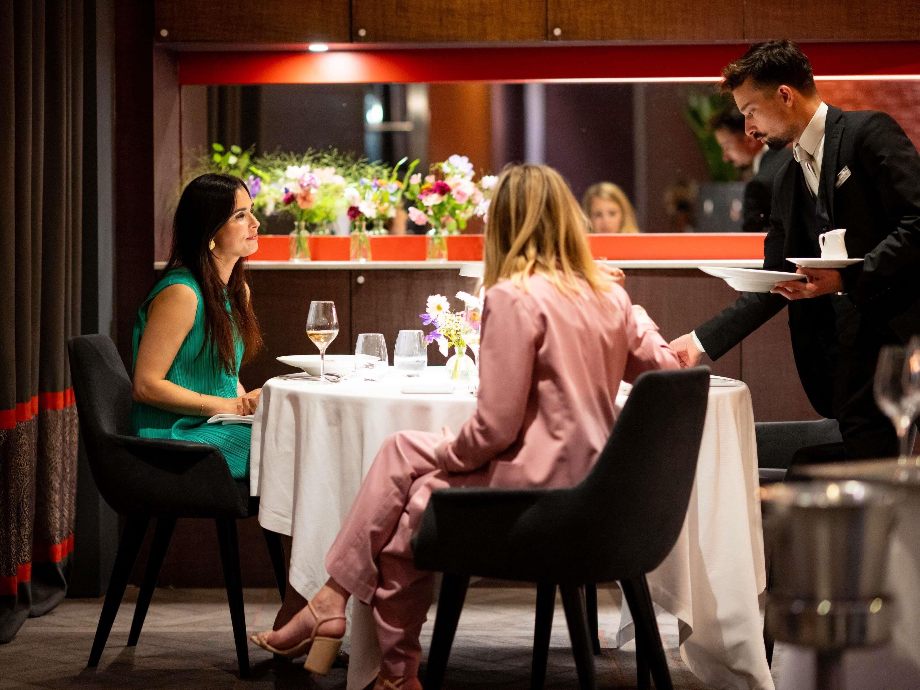 A dining area with tables, chairs, and a waiter.