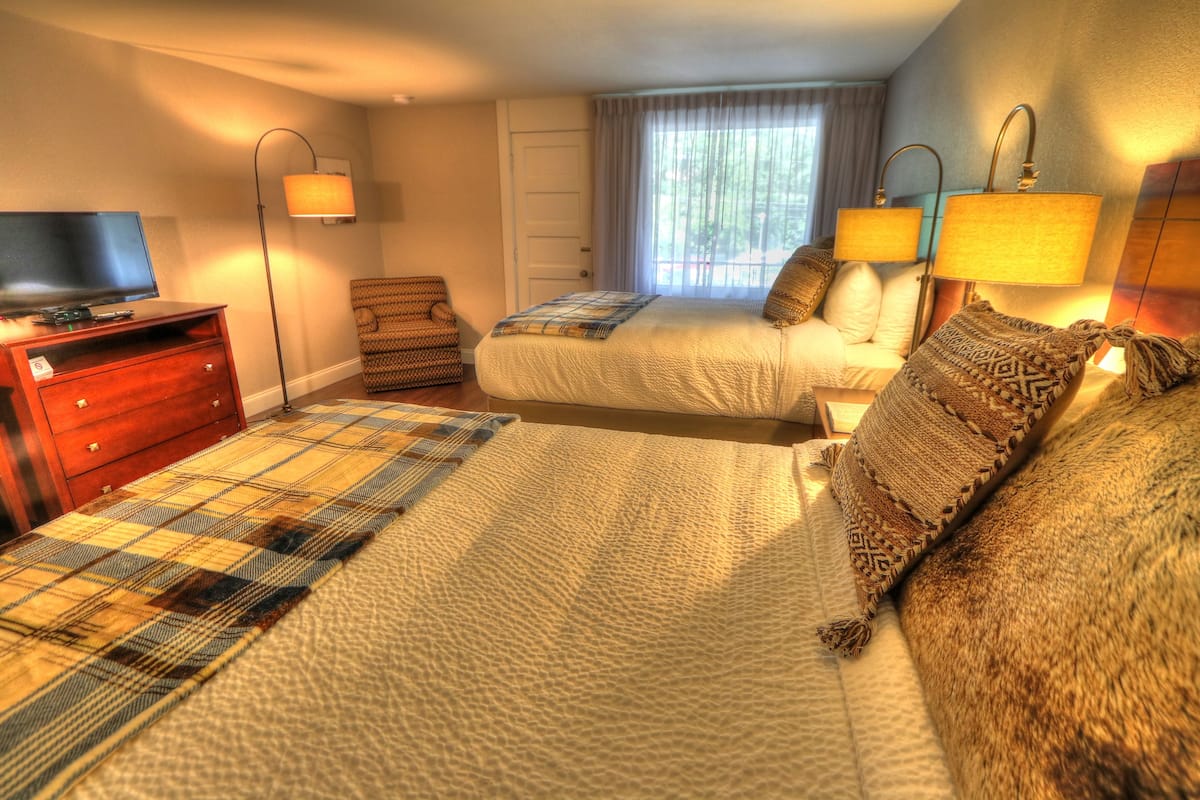 Quarto de hotel com uma cama grande, televisão, escrivaninha e uma cadeira.