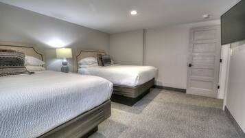 Une chambre d’hôtel avec deux lits, une table de chevet avec une lampe, une porte et une petite fenêtre.