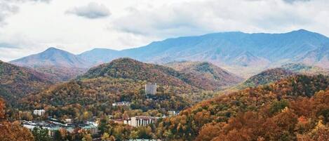 A town nestled in a valley with autumn foliage, surrounded by mountains.