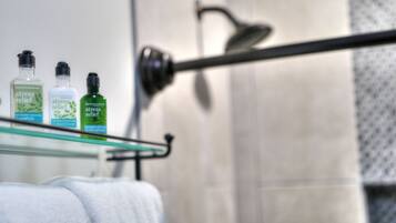 Ein Badezimmer mit einer Glasablage, auf der drei Shampoo- und Conditionerflaschen stehen.