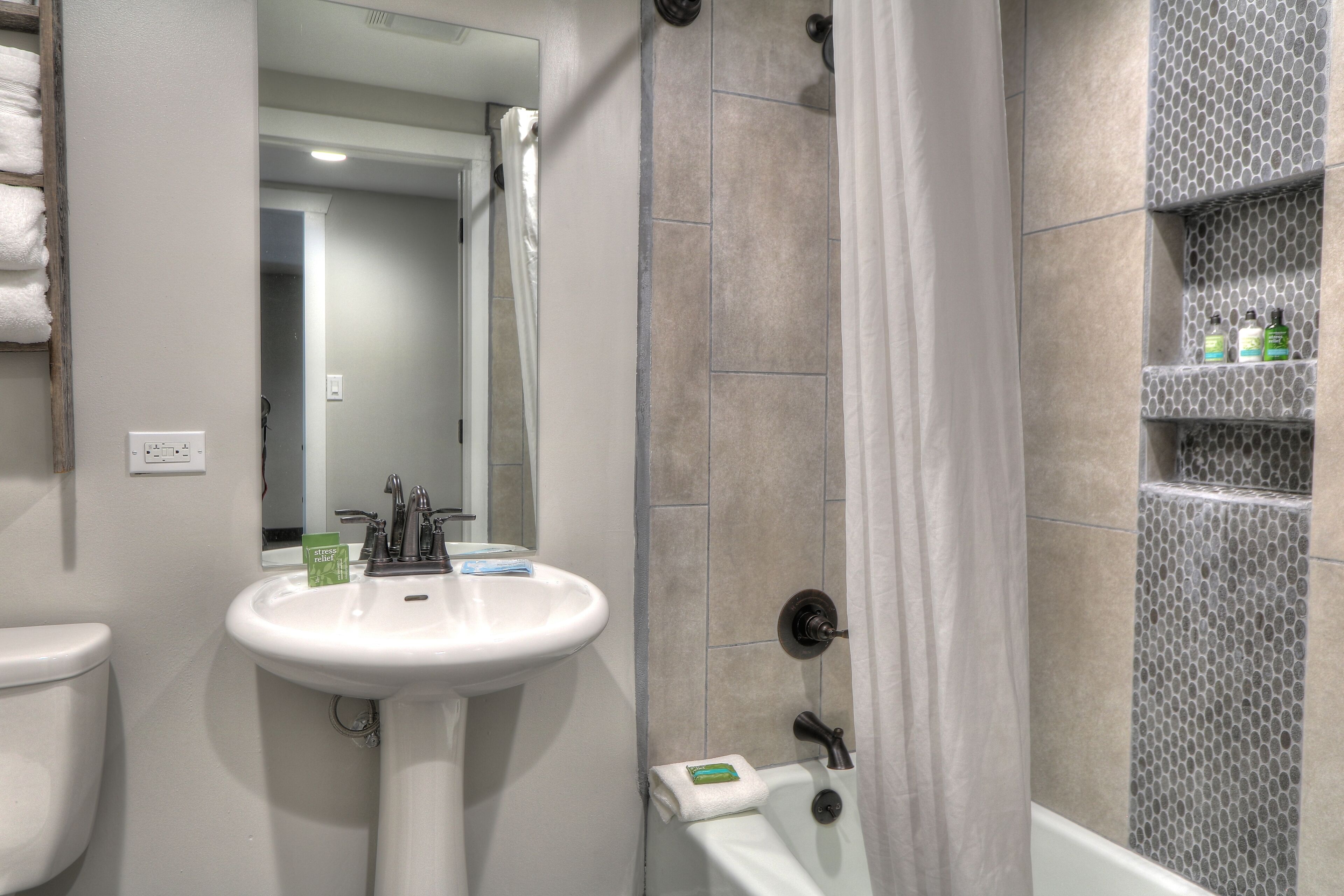 Un baño con lavamanos blanco, inodoro, ducha con puerta de vidrio y espejo.