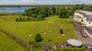 Un amplio espacio cubierto de césped, con mesas de picnic y un edificio con un gran jardín al fondo.