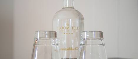 A bottle of Bloomfield Stillwater and two glasses on a table.
