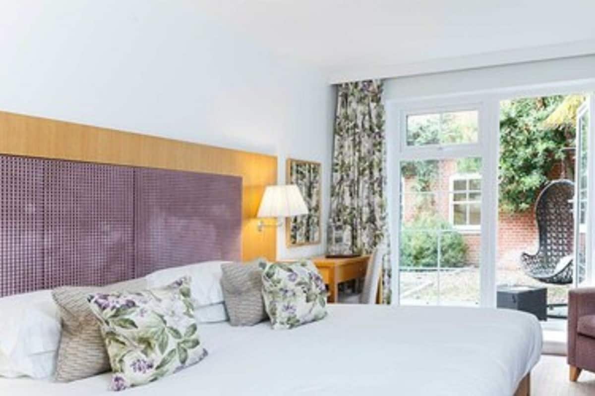 A hotel room with a bed, a chair, a lamp, and a view of the outside.