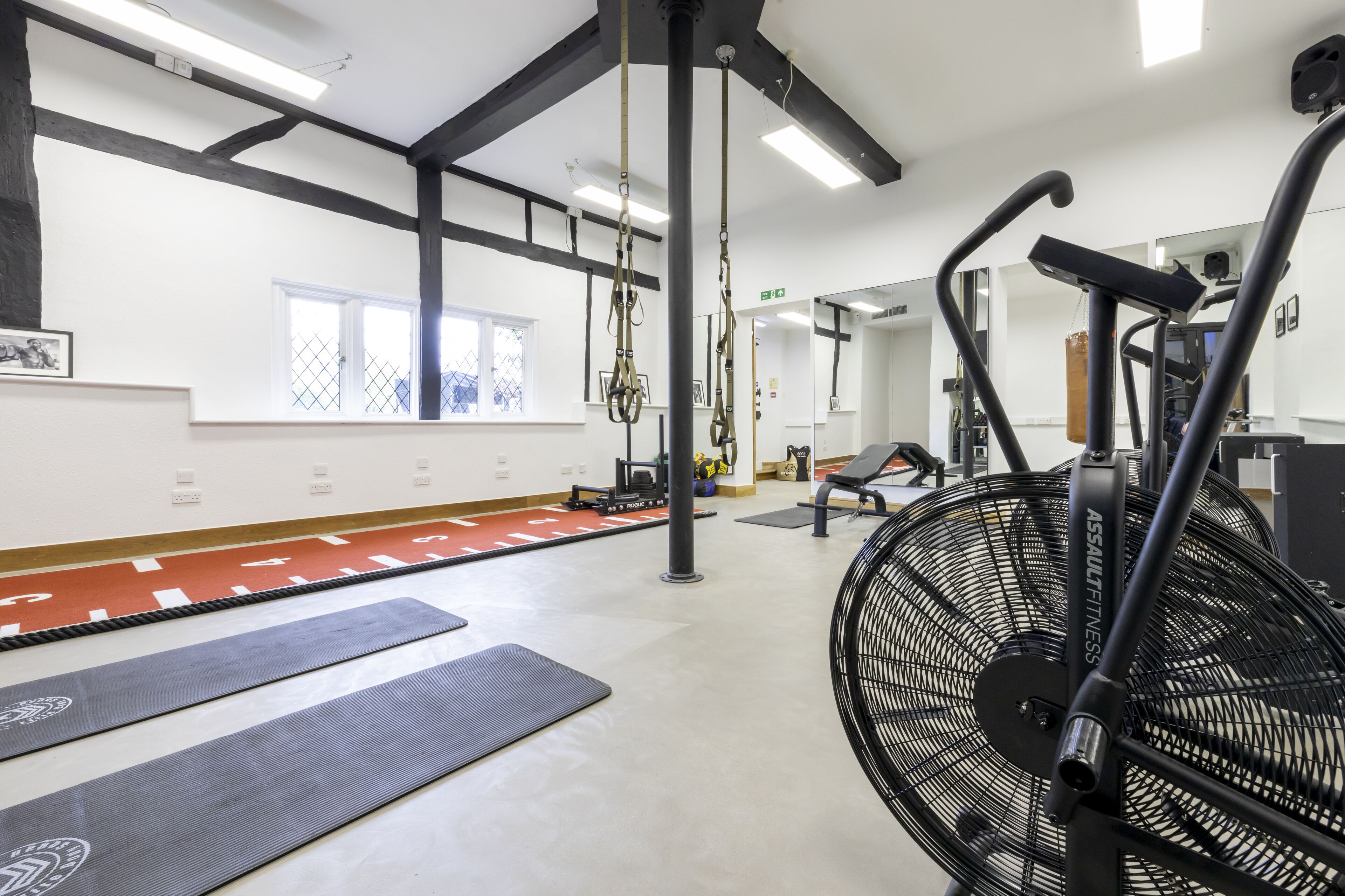 A gym with exercise equipment, mats, and a large fan.