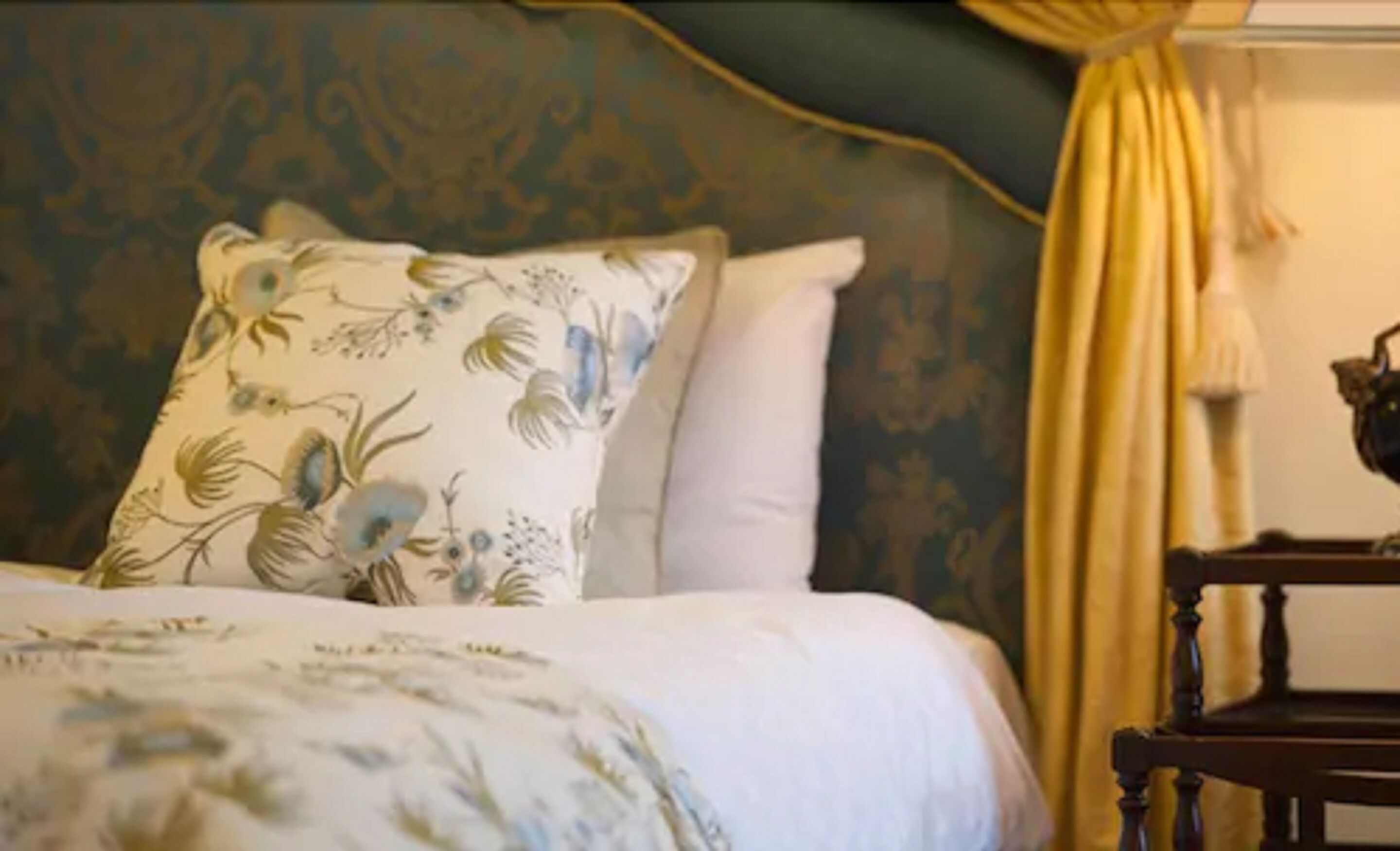 A bed with floral-patterned pillows and a plain white bedspread.