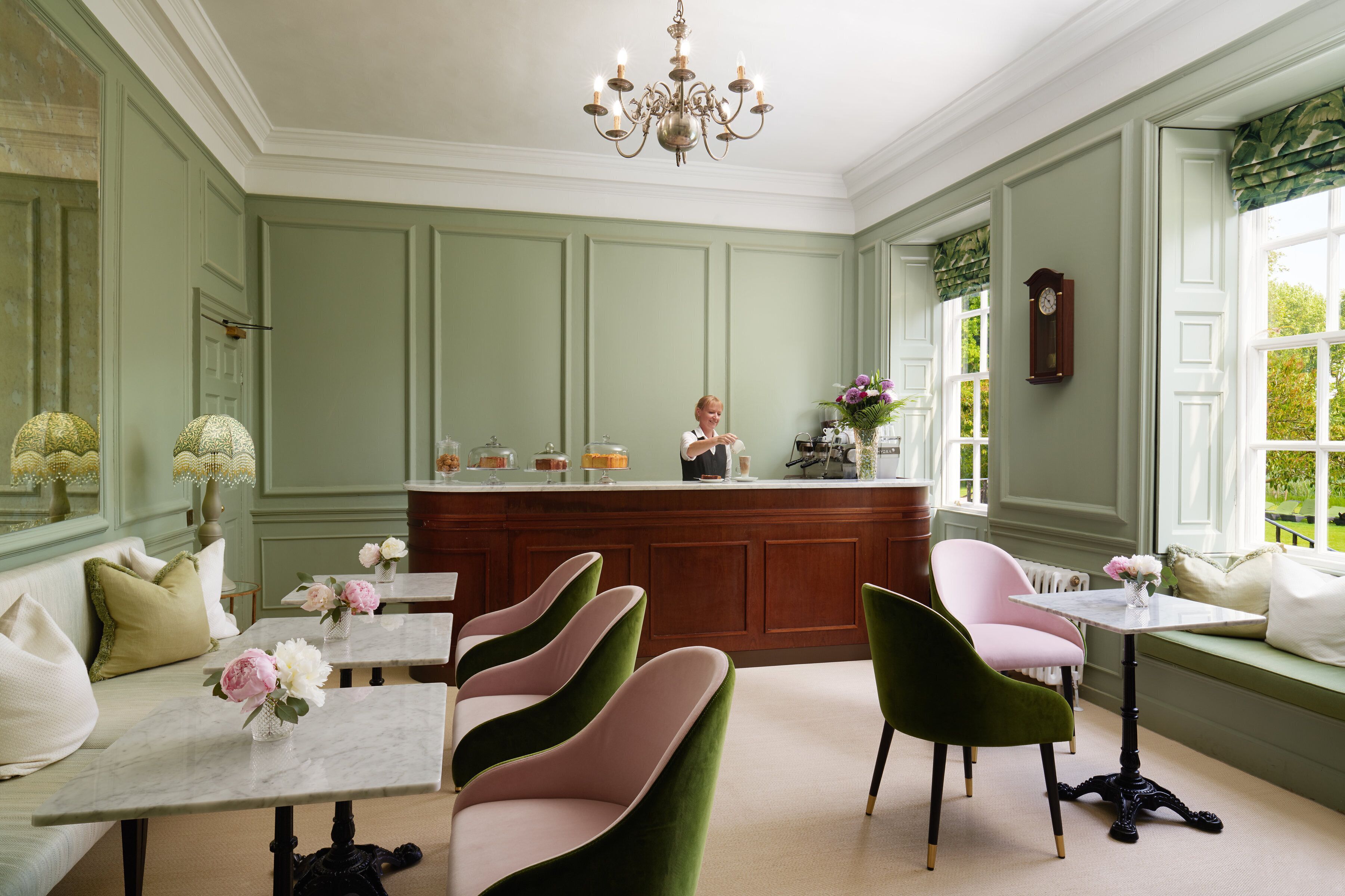 Een kamer met een groene wand, een houten bar, een witte tafel en een bank.