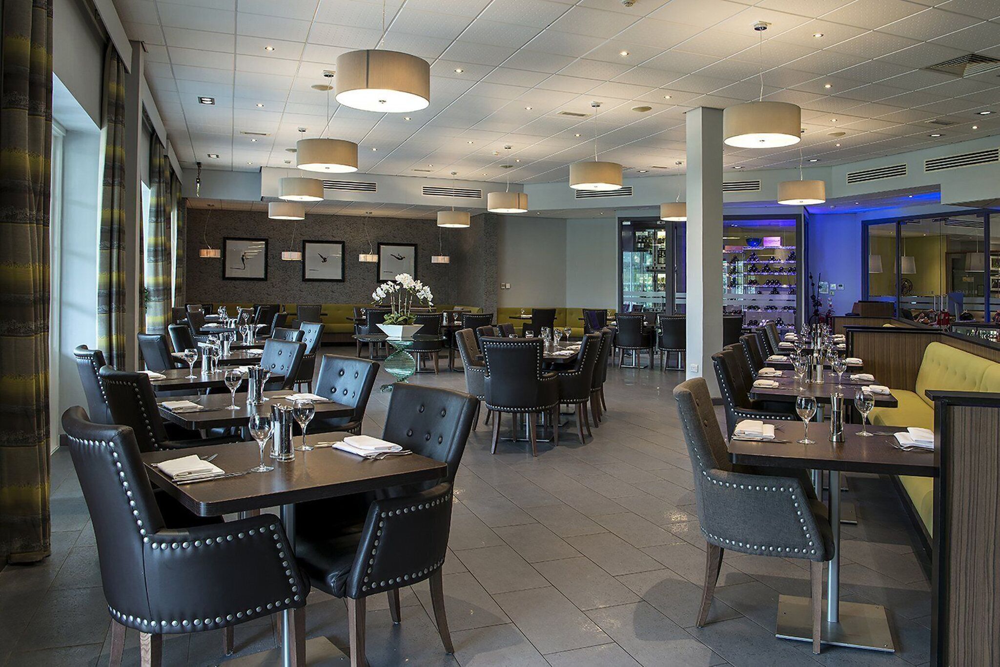 Ein Restaurant mit mehreren Tischen und Stühlen, einer Bar und gerahmten Kunstwerken an den Wänden.