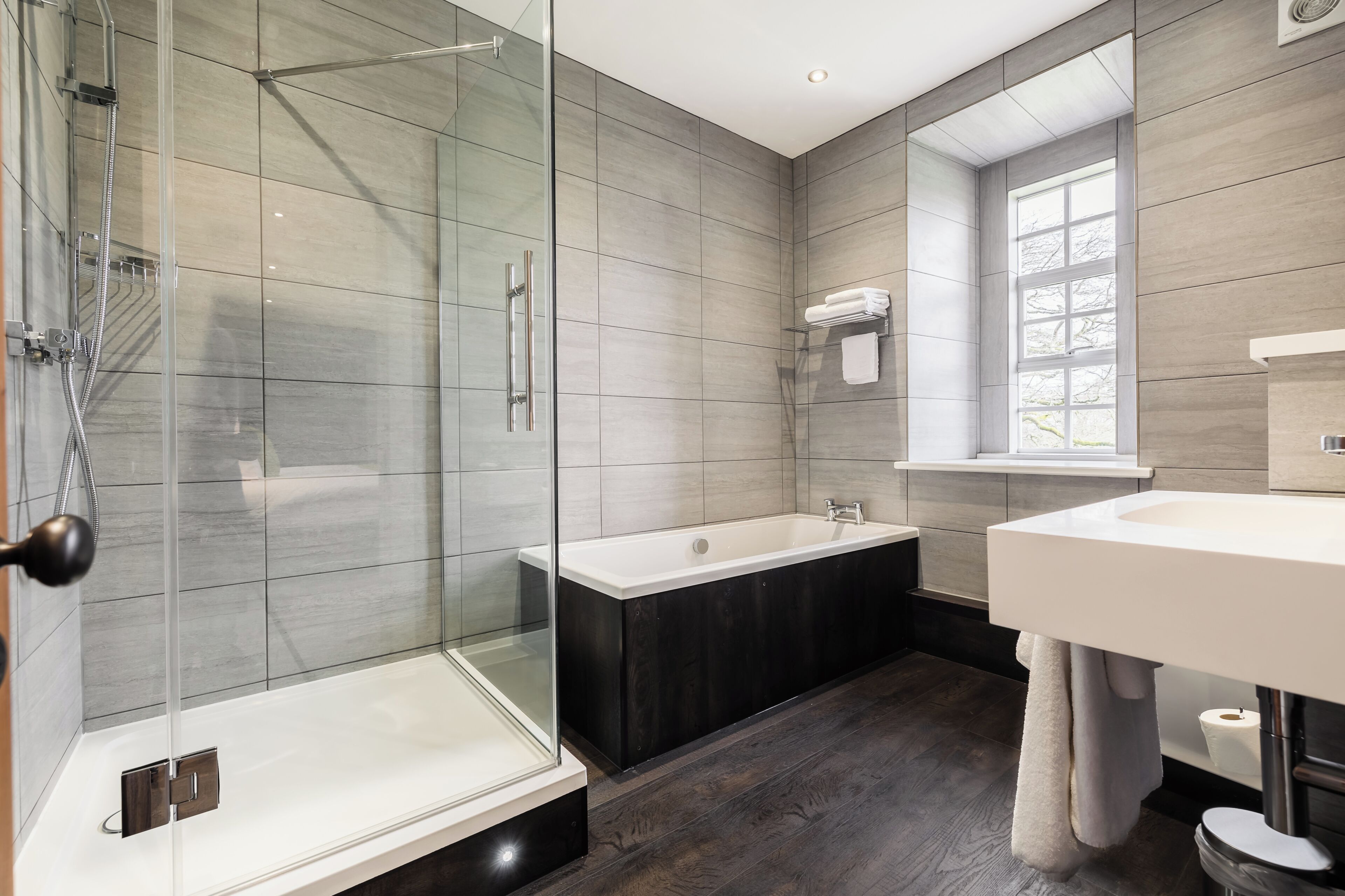 Une salle de bain moderne avec une douche à parois de verre, une baignoire sur pieds et un grand miroir au-dessus du lavabo.