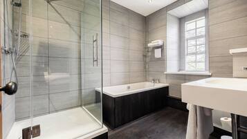 Ein modernes Badezimmer mit einer gläsernen Duschkabine, einer freistehenden Badewanne und einem großen Spiegel über dem Waschbecken.