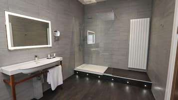 A modern bathroom with a large mirror, a vanity with a sink, and a shower area.