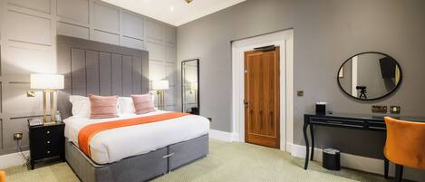Una habitación de hotel moderna con una cama grande, lámparas de noche, un escritorio, una silla y un espejo.