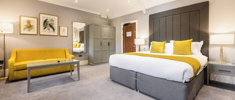Una habitación de hotel moderna con una cama grande, un sofá, un armario y cuadros en la pared.