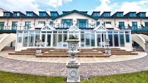 A hotel with a central courtyard featuring a fountain, a conservatory, and a staircase leading to the upper floors. - Vale Resort (Pontyclun)
