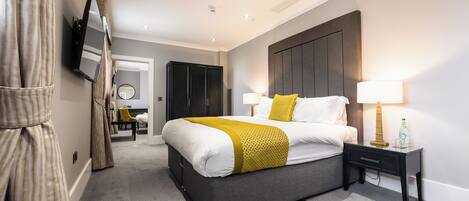 A modern hotel room with a bed, bedside tables, a TV, and a wardrobe.