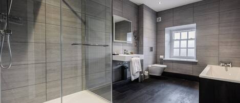 A modern bathroom with a glass-enclosed shower, a large mirror, a bathtub, and a window.