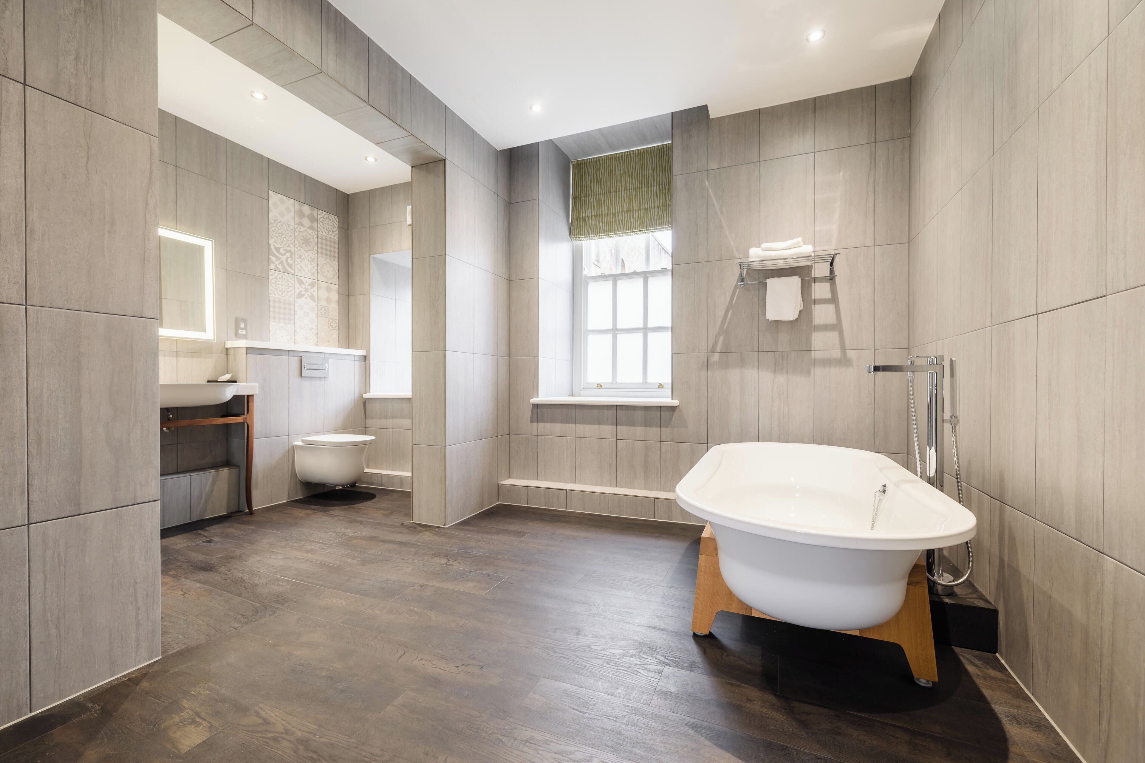 Een moderne badkamer met een vrijstaand bad, een toilet en een wastafel met spiegel.