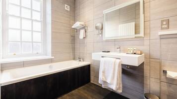 Un baño moderno con una bañera, un tocador con espejo y una ventana.