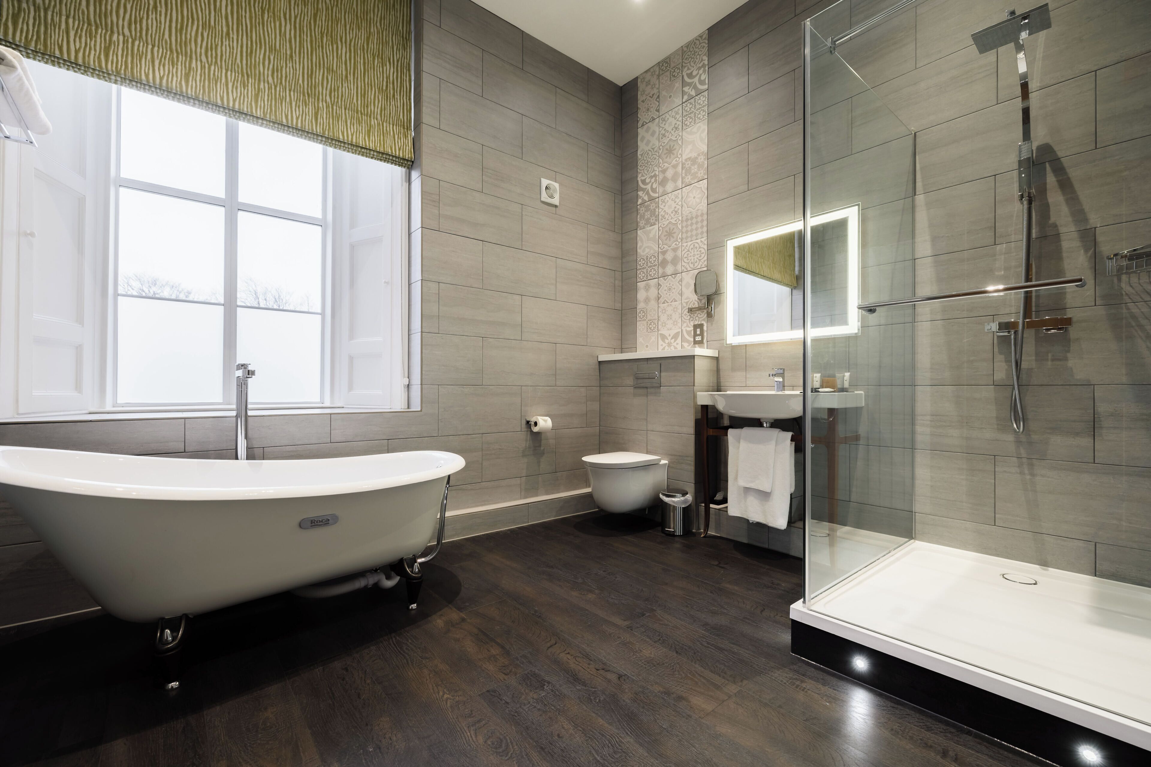 Un baño moderno con una bañera independiente, una ducha con cerramiento de vidrio y un inodoro.
