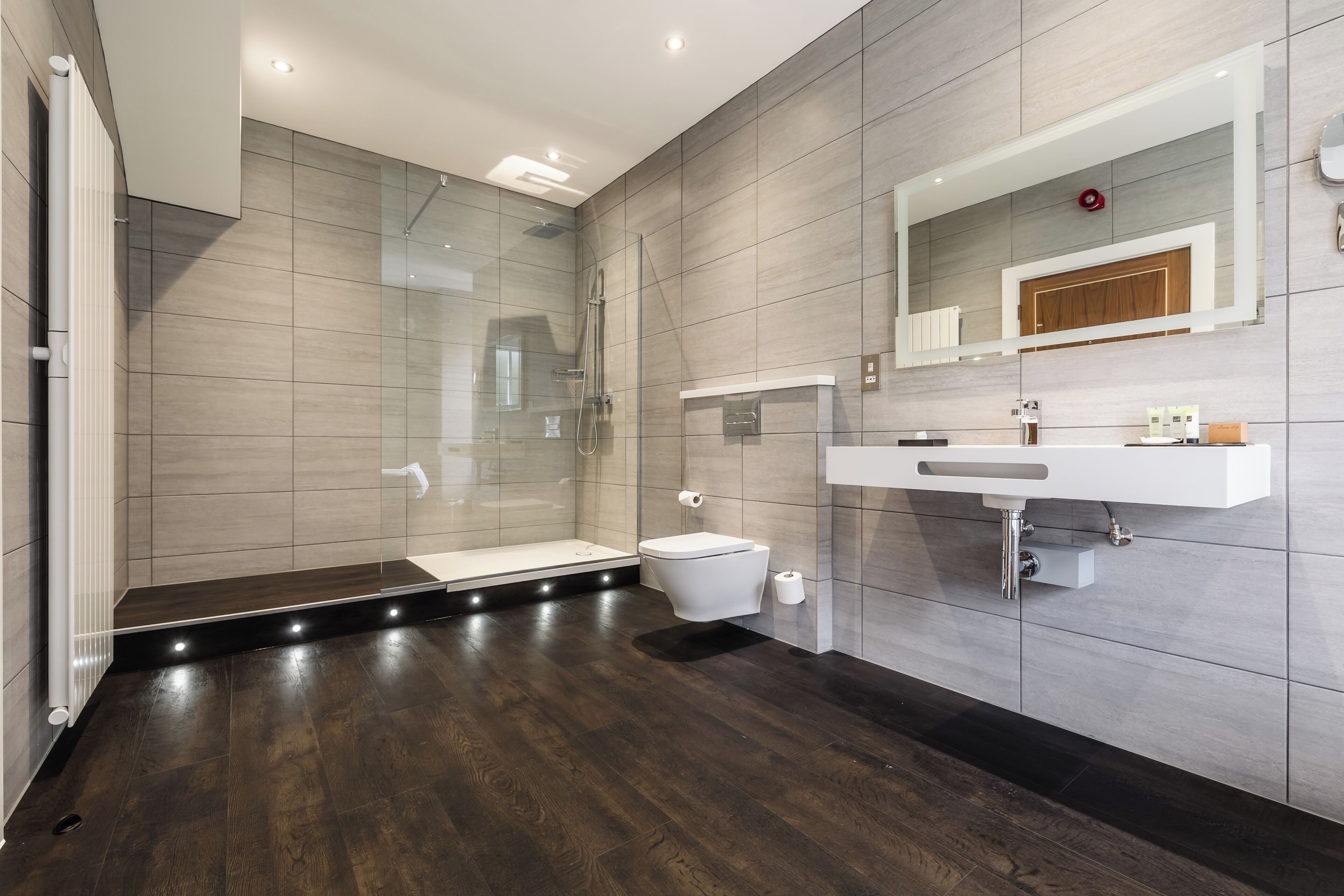 A modern bathroom with a glass shower enclosure, a toilet, and a vanity with a mirror.