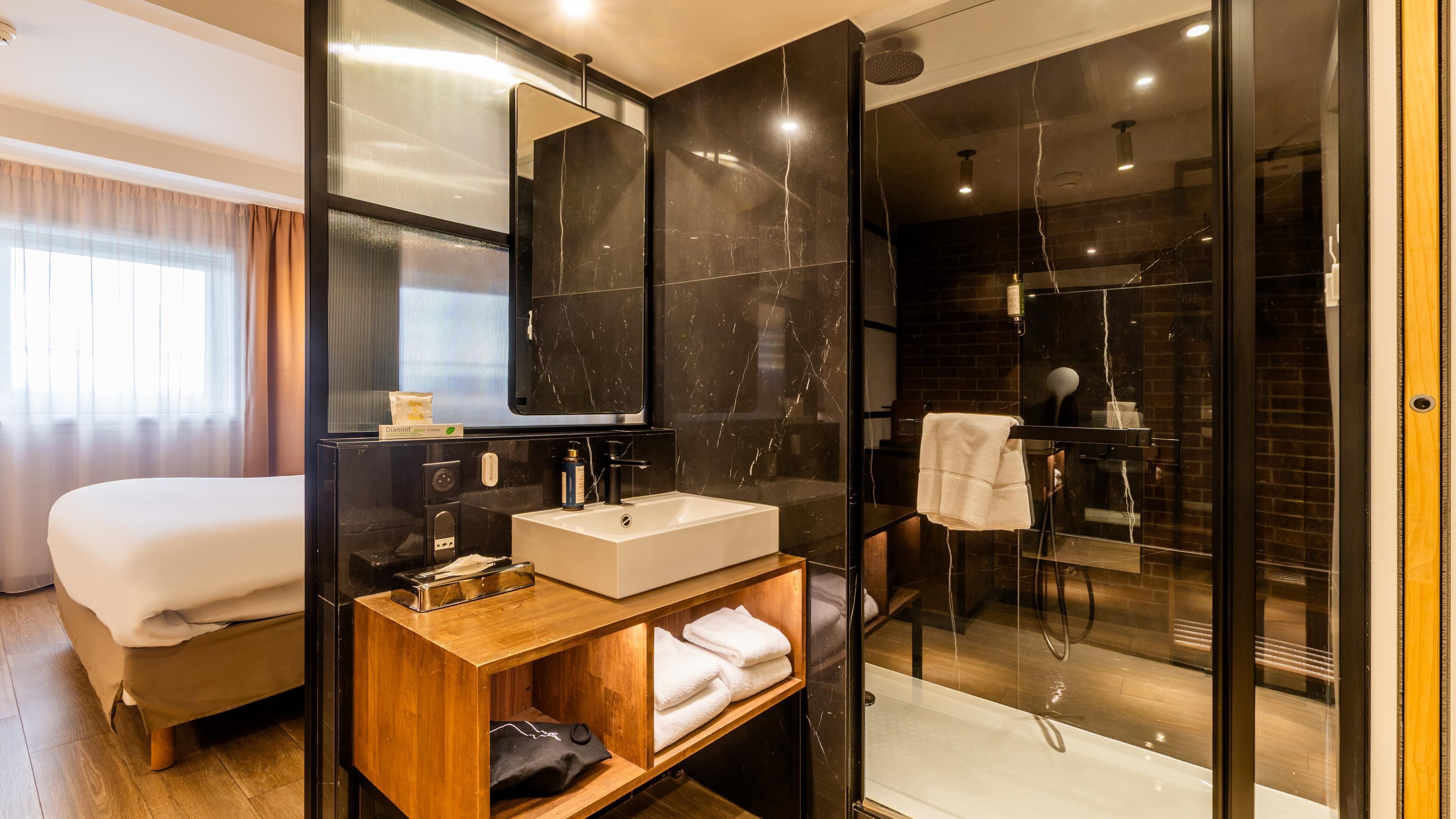 Une salle de bain moderne avec une douche à parois de verre, un meuble-lavabo en bois et un grand miroir.