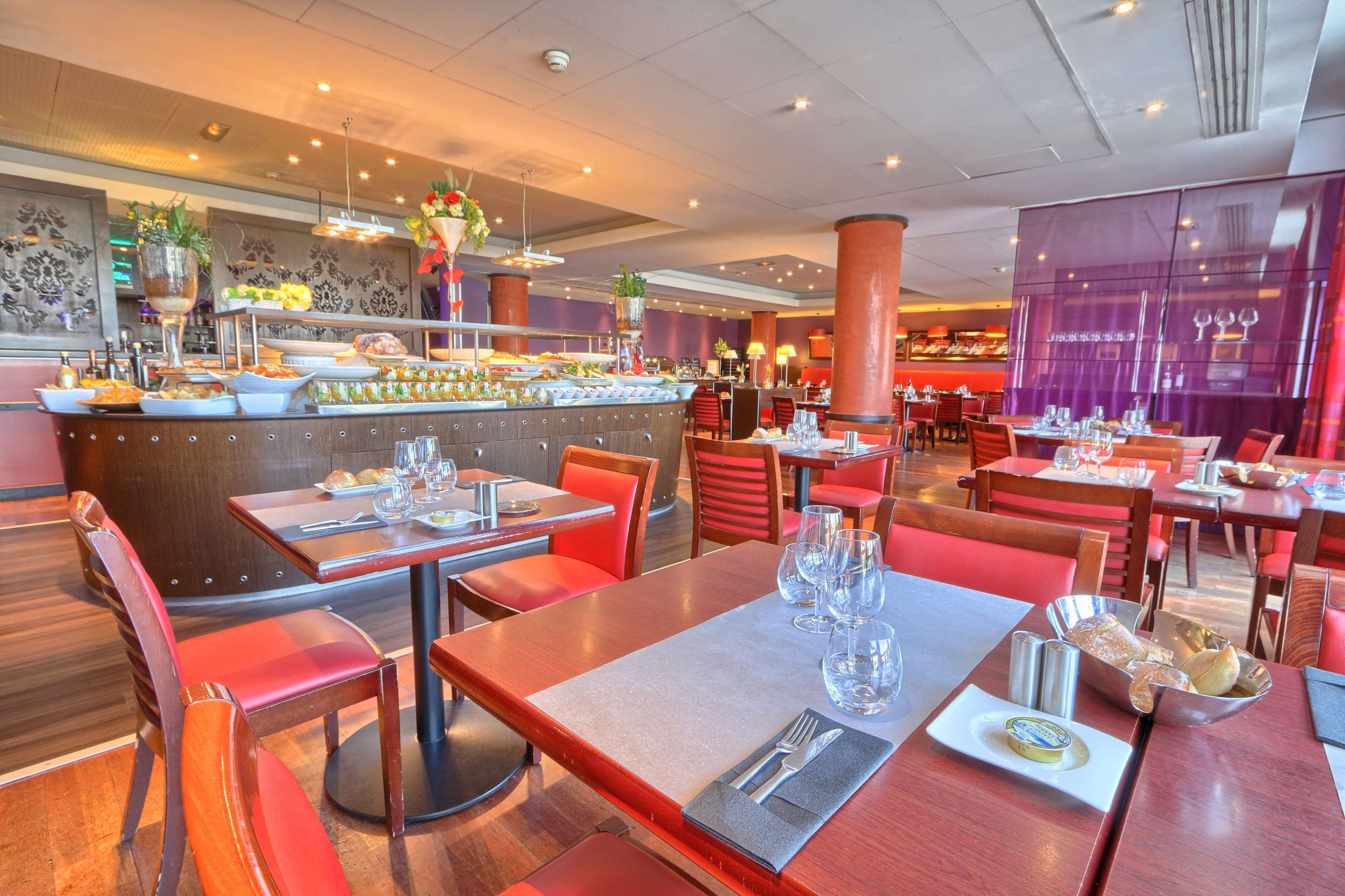 Un restaurant doté de nombreuses tables, de chaises rouges et d’un espace buffet proposant une variété de plats.