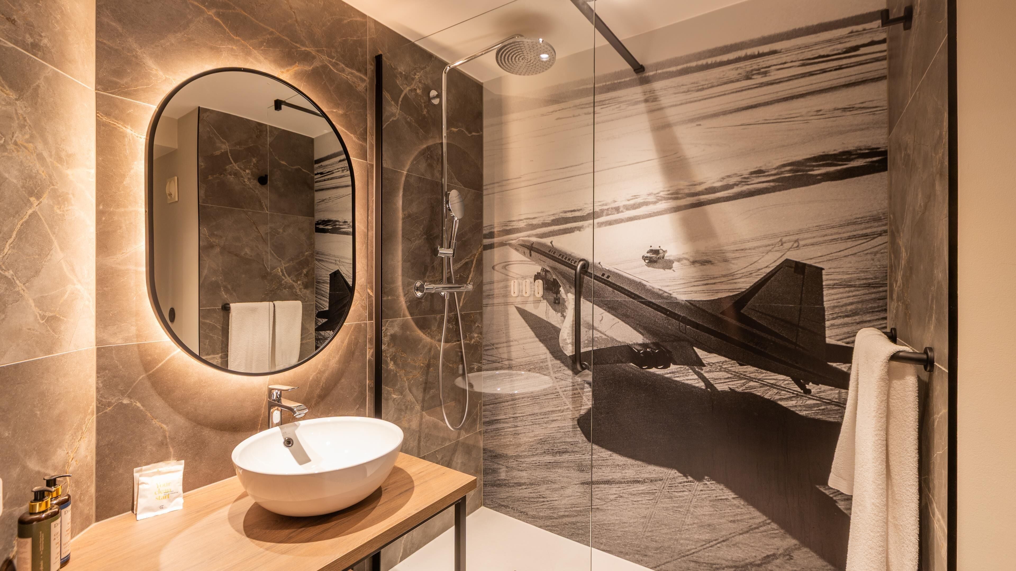 Une salle de bain moderne avec un miroir rond, un lavabo et une douche.