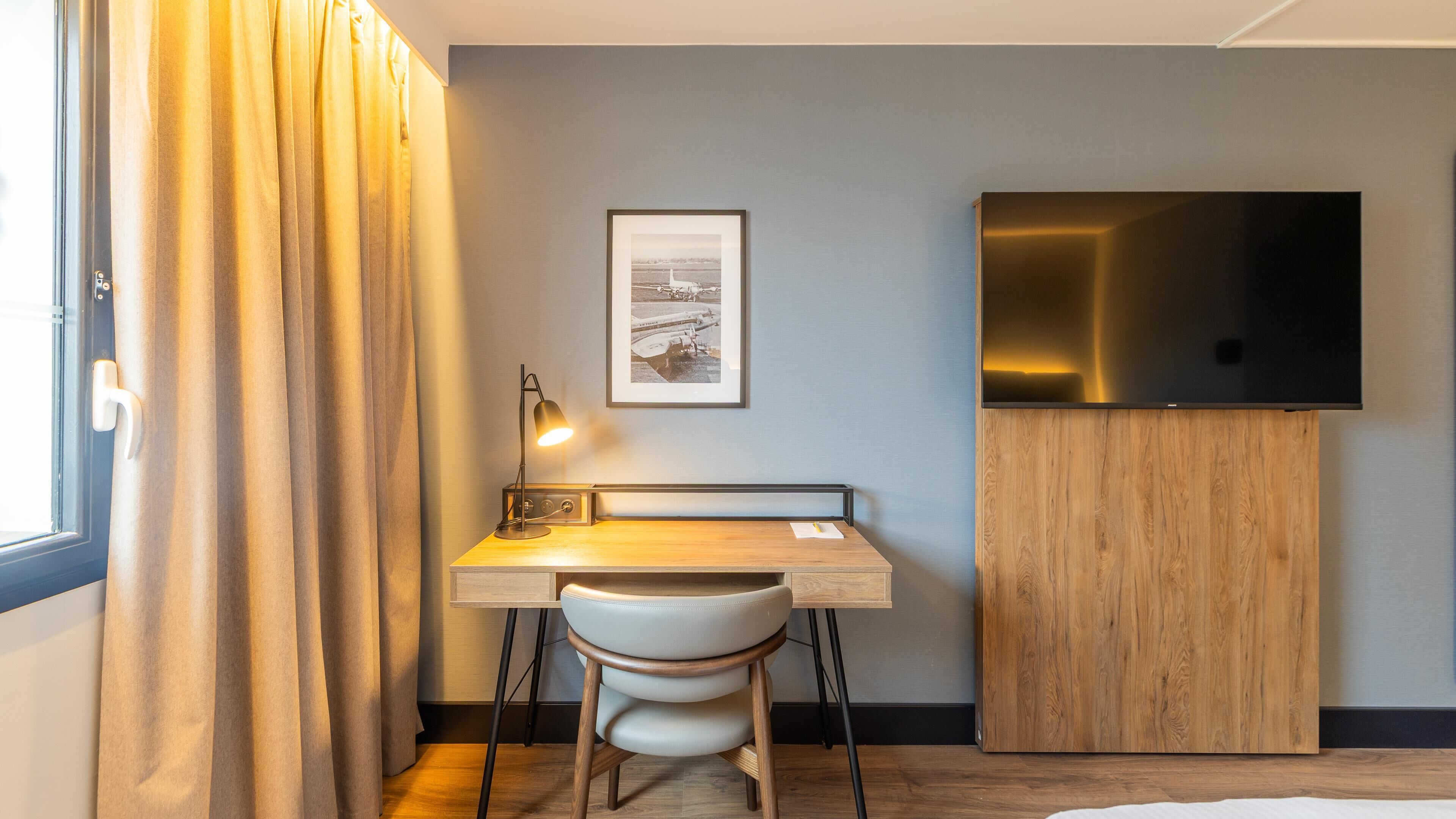 A modern room with a desk, chair, and TV.
