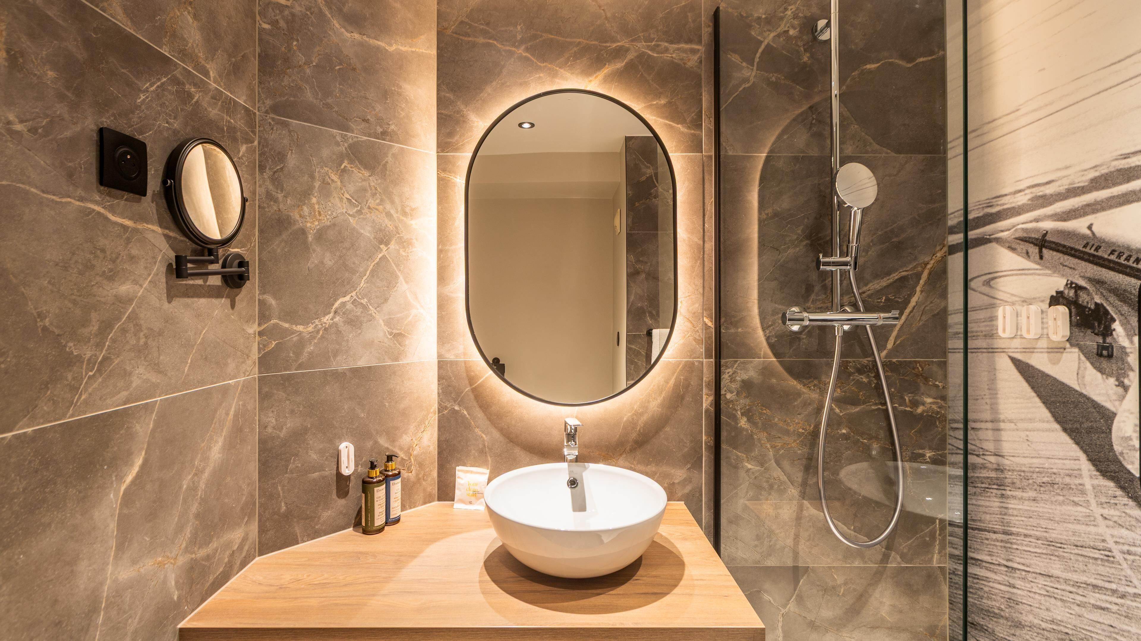 Ein Badezimmer mit rundem Spiegel, Waschbecken und Dusche.