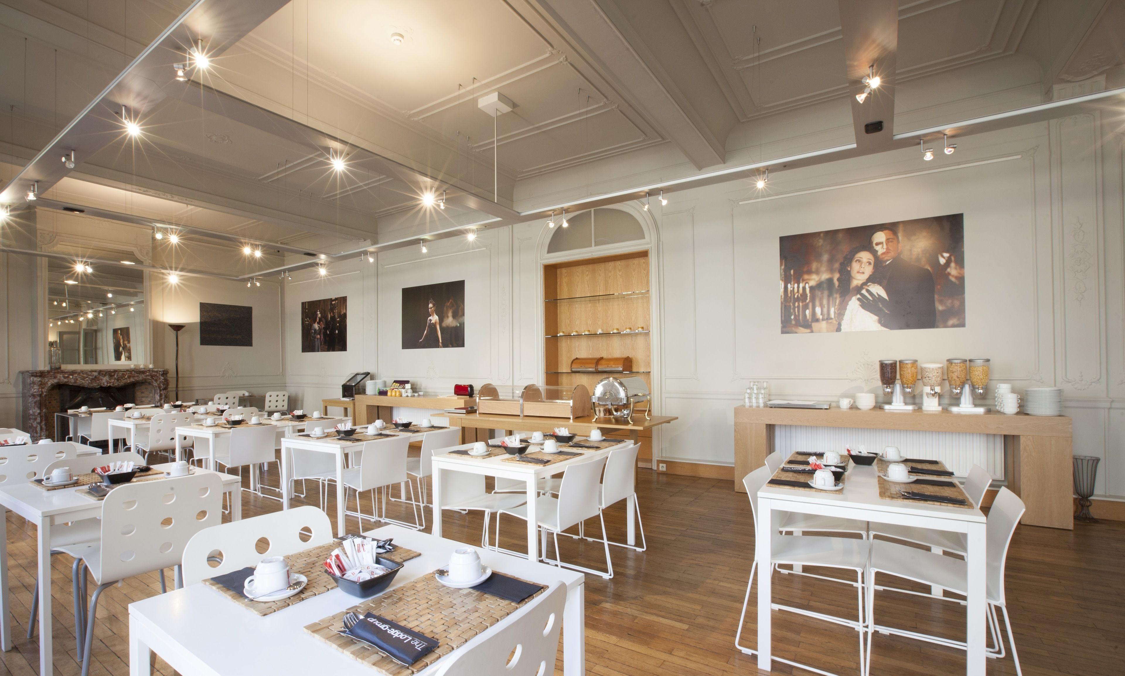 A spacious dining area with multiple tables and chairs, a fireplace, and a wall with framed pictures.