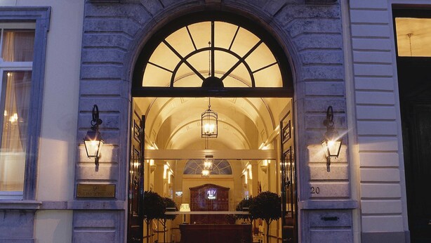 A grand entrance with an arched doorway, a reception desk, and a chandelier.