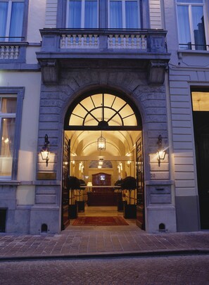 Une entrée imposante avec un portail en arc de cercle, un comptoir d’accueil et un lustre.