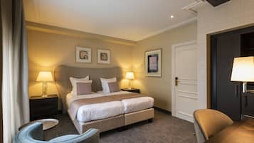 A hotel room with a bed, two bedside tables with lamps, a chair, and a door.