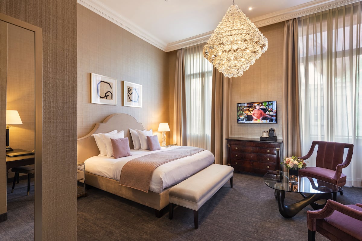 Ein Hotelzimmer mit einem großen Bett, einem Fernseher, einem Schreibtisch und einem Sessel.