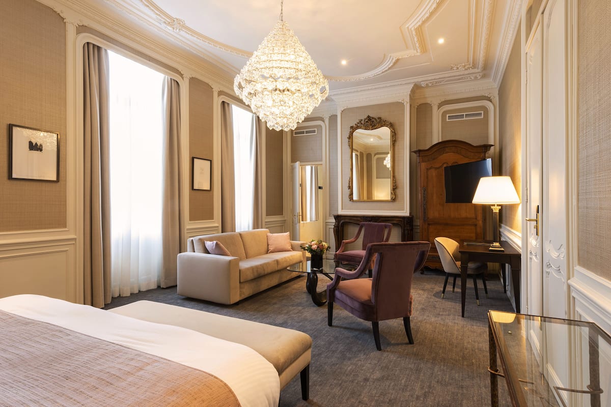 Ein Hotelzimmer mit einem großen Bett, einer Couch, einem Sessel, einem Tisch und einer Deckenleuchte.