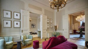 A spacious living room with a chandelier, framed artwork, and a mix of modern and classic furniture.