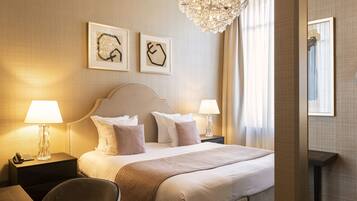 A hotel room with a large bed, two bedside tables with lamps, a chair, and artwork on the wall.