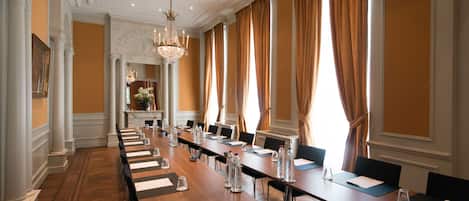 A conference room with a long table, chairs, water bottles, and a chandelier.