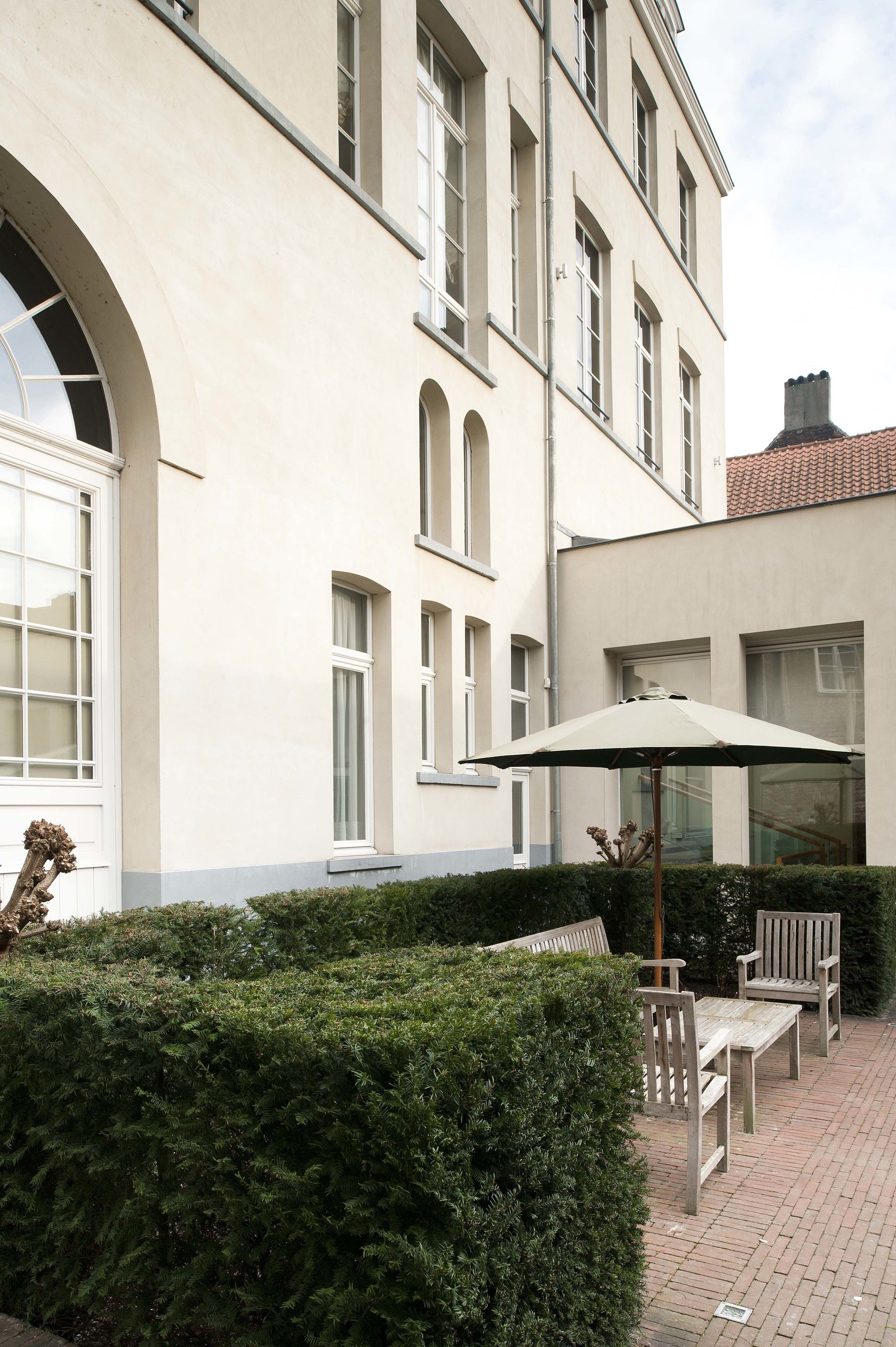 A building with a courtyard, a bench, and an umbrella.