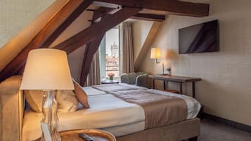 Ein Hotelzimmer mit Bett, Schreibtisch, Lampe und Fernseher.