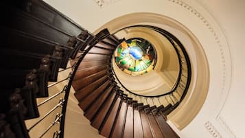 Un escalier en colimaçon surmonté d’une fenêtre à vitraux.