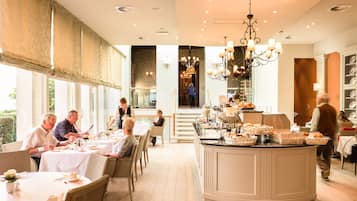 A dining area with tables set for guests, a central serving station, and a staircase leading to an upper level.