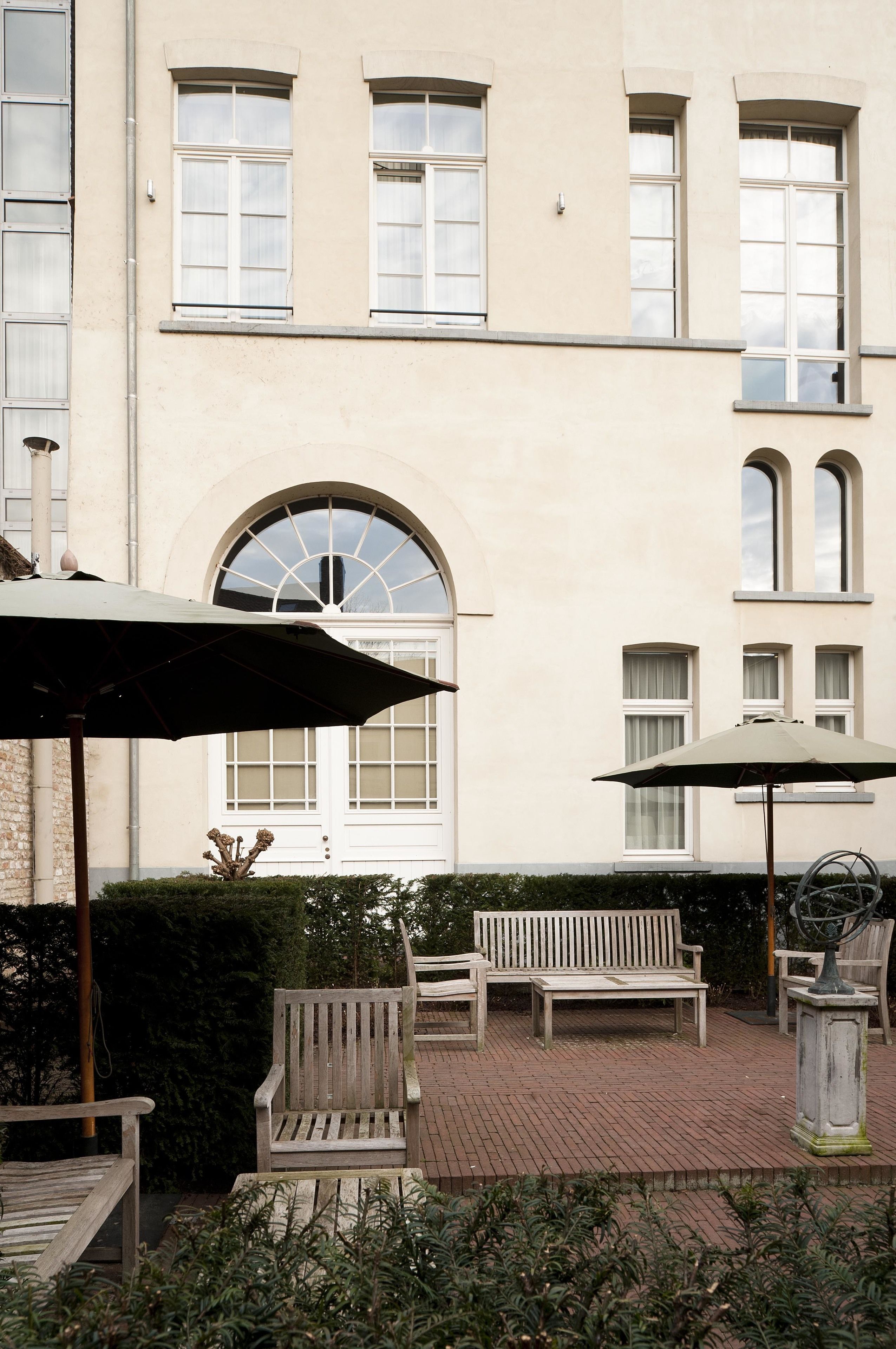 A courtyard with a bench, two umbrellas, and a statue.