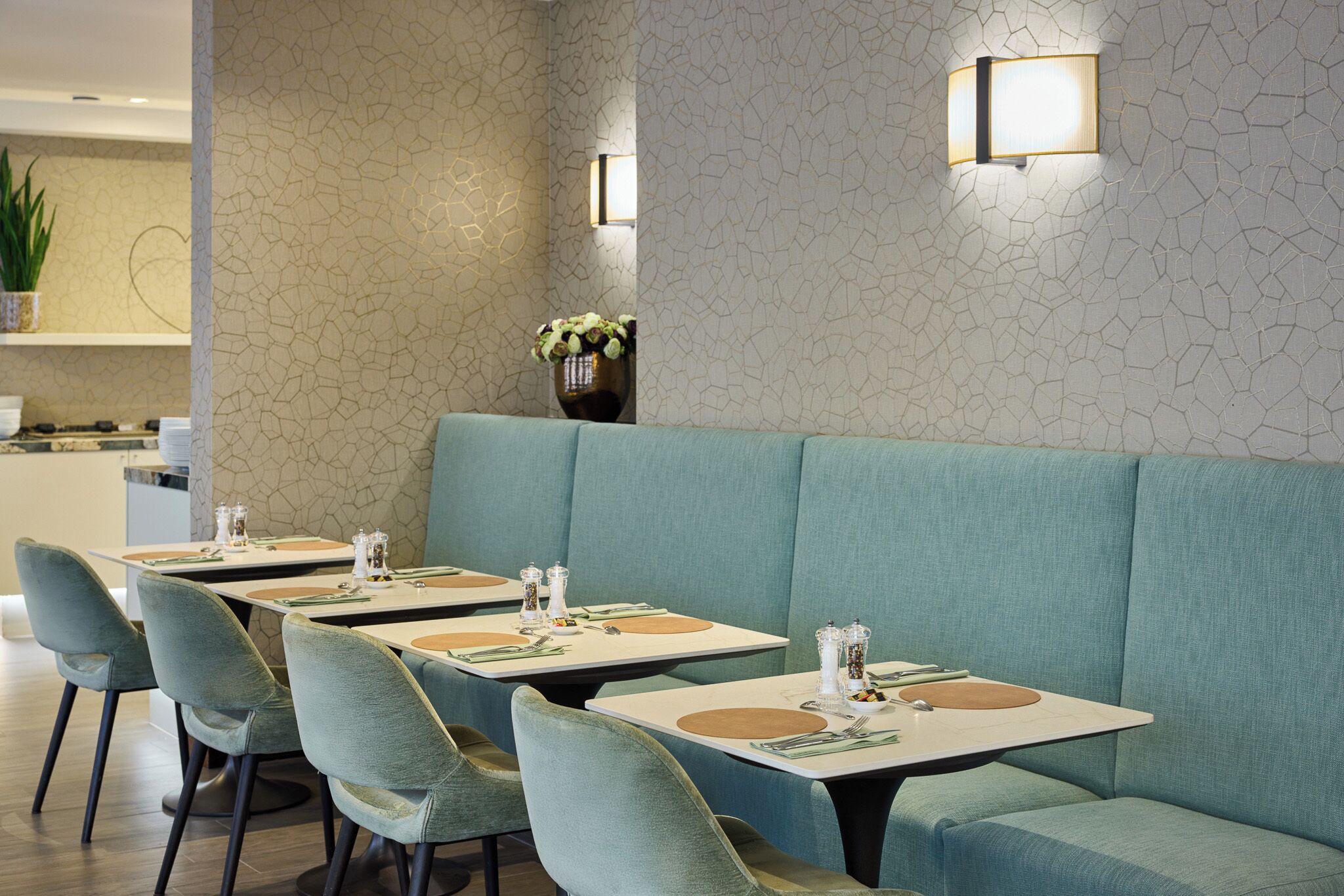 Ein Restaurant mit senffarbenen gepolsterten Sitzecken, quadratischen Tischen und passenden Stühlen.