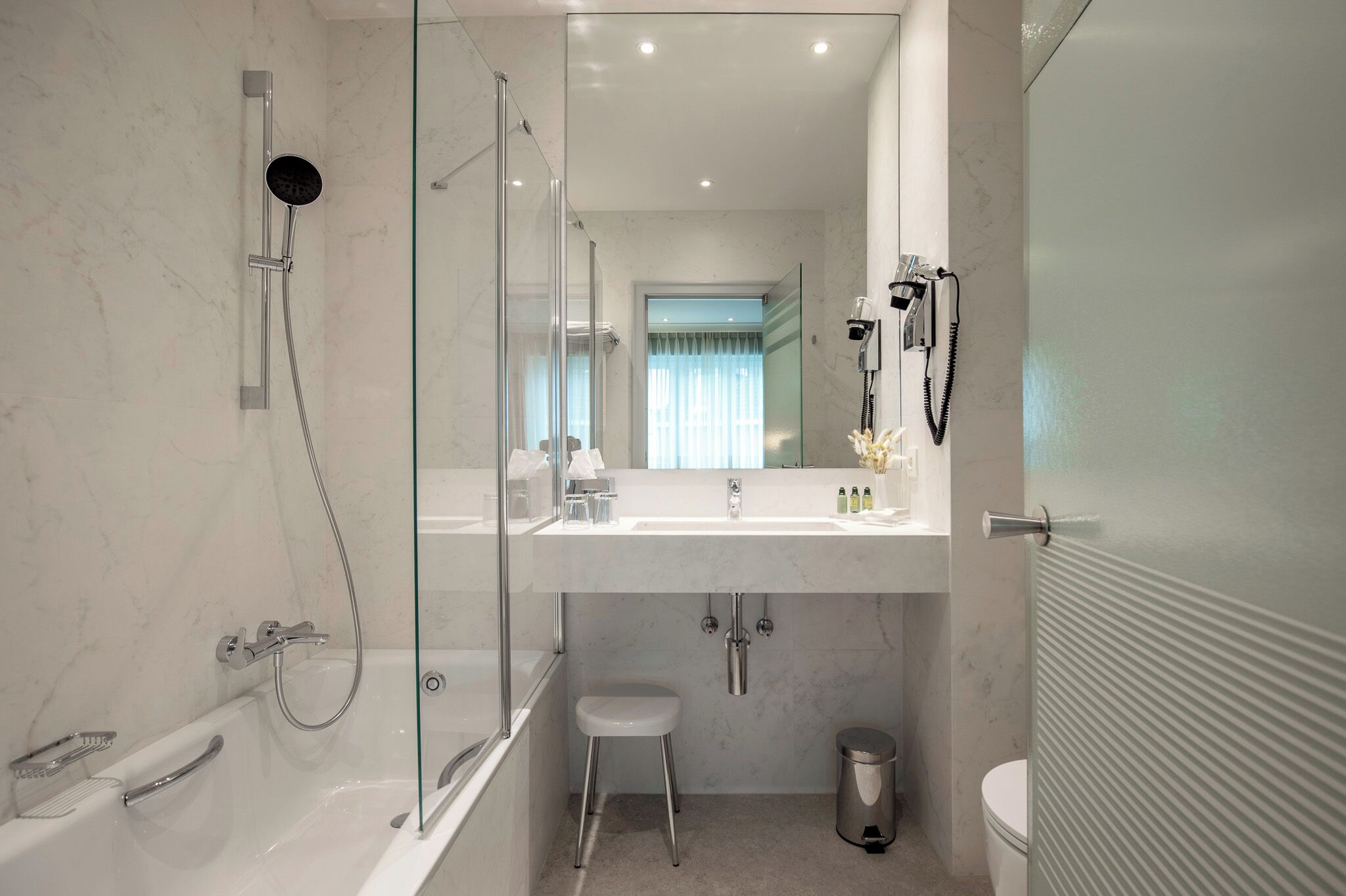 Ein modernes Badezimmer mit einer Glasdusche, einem weißen Waschbecken mit Spiegel und einer Toilette.