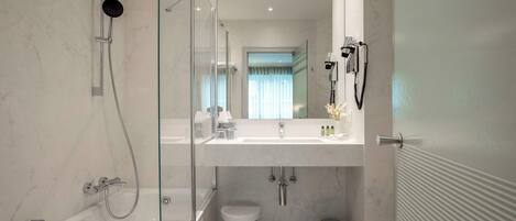 Ein modernes Badezimmer mit einer Glasdusche, einem weißen Waschbecken mit Spiegel und einer Toilette.
