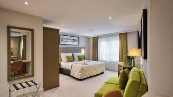 Una habitación de hotel con una cama, un sofá verde, un escritorio y un espejo.