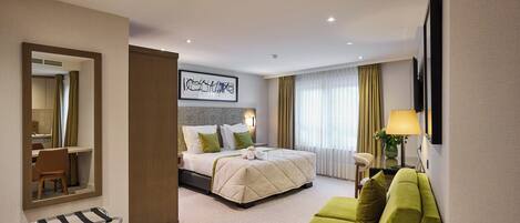Una habitación de hotel con una cama, un sofá verde, un escritorio y un espejo.